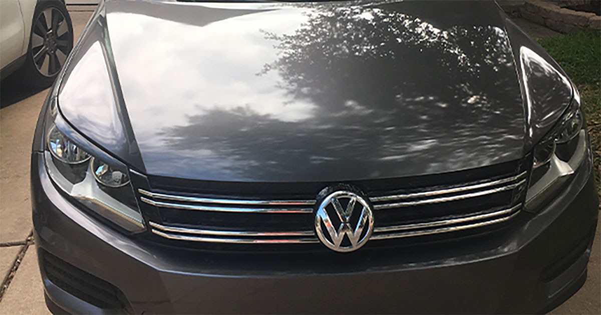 Front view of a gray Volkswagen car with reflections on the hood.